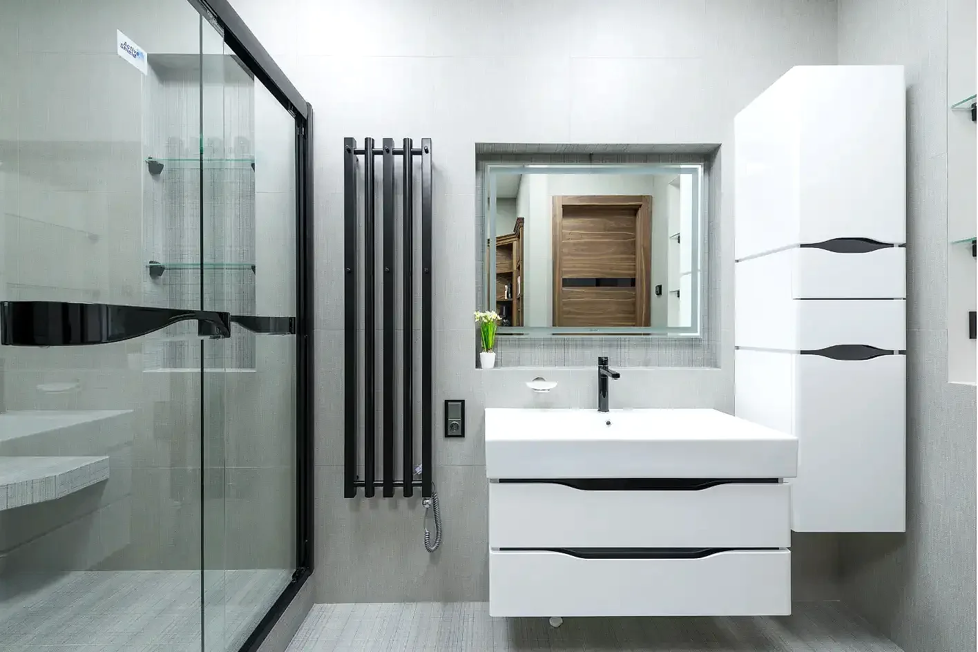 Siyah profilli duşakabin, siyah havlupan ve modern banyo dolapları.