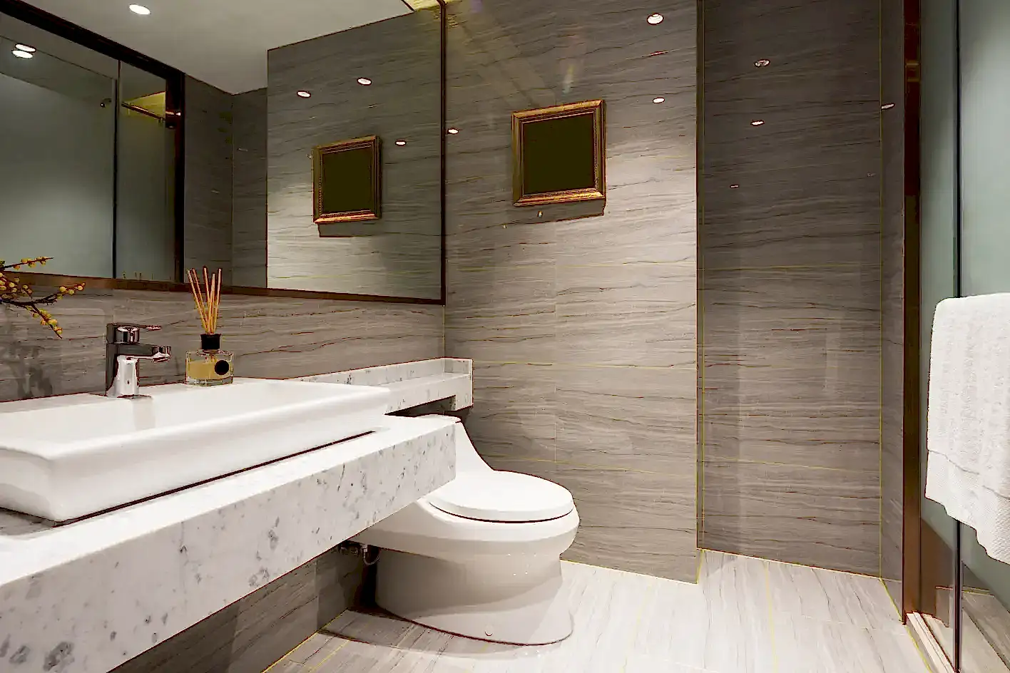 Mermer tezgahlı, gold detaylı gri lüks banyo tasarımı.