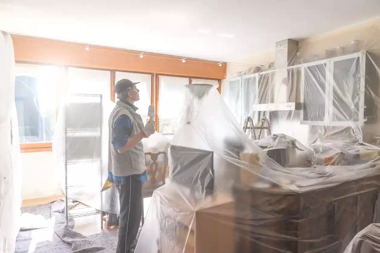 Koruyucu örtülerle kapatılmış eşyalı evde boya yapan usta.
